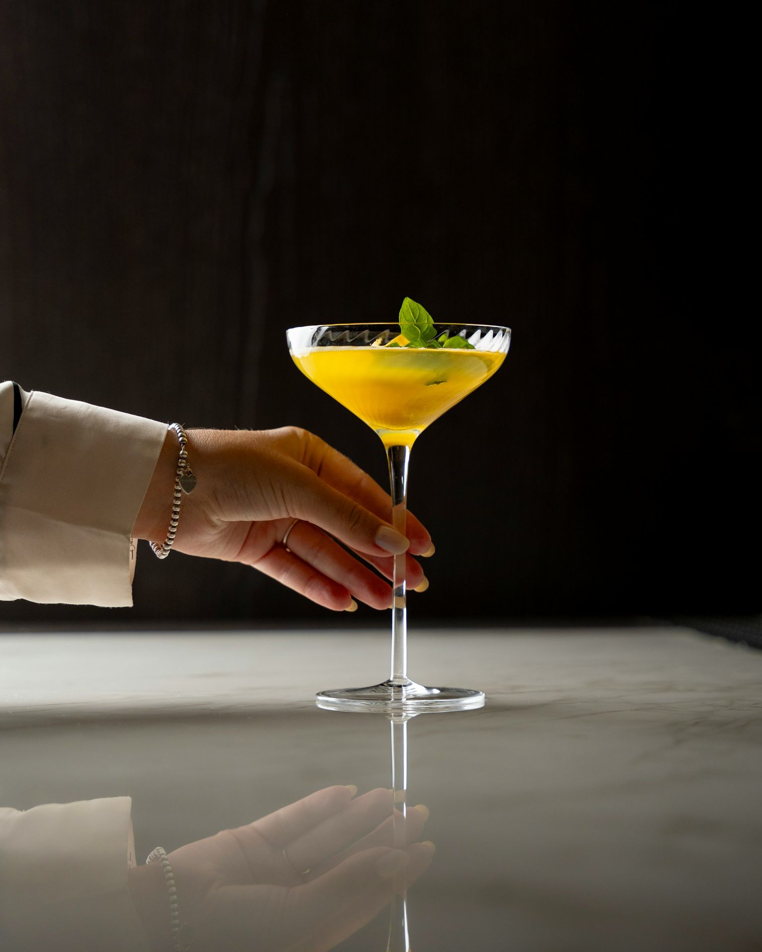 A hand reaching for a drink in a martini glass